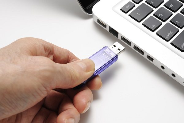 A hand inserting a flash drive in to a laptop port